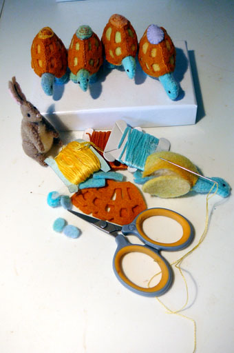 Stitching tiny hare and tortoise game pieces from wool felt