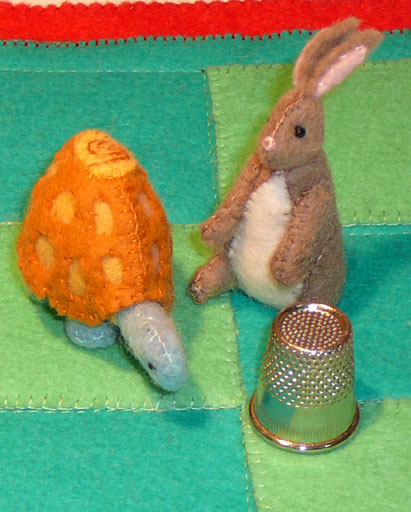 finished hare and tortoise on game mat with a thimble to indicate size